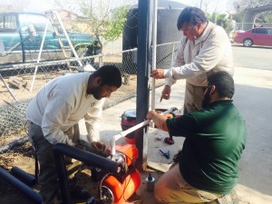 El equipo de Community Service and Employment Training instala las tubería en la bomba de agua.