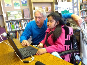 Un especialista en tecnología del distrito de Oakland, Chris Beatty, le ayuda a Jacqueline a usar una computadora para leer. Foto: Zaidee Stavely.