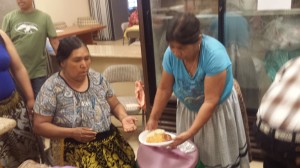 Cocineras purépechas sirviendo platillo de barbacoa y una corunda a voluntarios. Foto: Rubén Tapia.