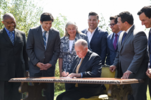 El gobernador Jerry Brown, acompañado de legisladores firma la ley que refuerza el compromiso para reducir las emisiones de gases de efecto invernadero un 40 por ciento por debajo de los niveles de 1990 para el año 2030, y para invertir en las comunidades más afectadas por el cambio climático. Foto: Cortesía de la oficina del gobernador.