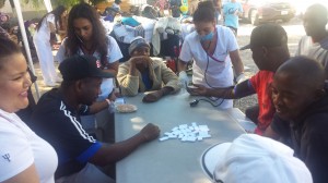 Estudiantes de enfermería de la escuela, Con Amor,  toman la presión de migrantes haitianos que juegan domino.