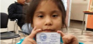 Esta niña inmigrante muestra con orgullo su credencial de Medi-Cal, que le da acceso a una cobertura completa que incluye dentista, con la nueva ley de California, SB 75.