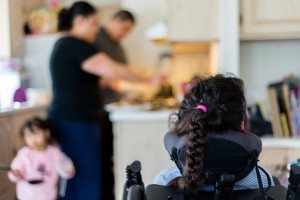 Abril sits in the living room while her parents make breakfast. Sonia and Rafael say the family always eats breakfast together and that dealing with Abril’s medical issues has made their family stronger. (Heidi de Marco/KHN)