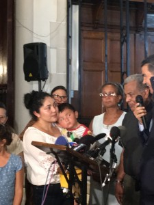 Amanda Morales Guerra con su hijo más pequeño en brazos, escucha al concejal de la ciudad Ydanis Rodríguez prometer a la inmigrando que hoy iría una delegación de funcionarios municipales y estatales al Departamento de Seguridad Interna (DHS) a pedir que paren su deportación. A su lado el padre Luís Barrios. Foto: MVG.