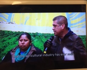 Gerardo Reyes y Guadalupe Gonzalo, de la Coalición de Trabajadores de Immokalee hablando sobre la industria de la comida y los campos de cultivo, en un video reproducido a través de una tableta electrónica colgada en la pared interior de la carpa museo, en la exhibición de la campaña ‘Cosecha sin Violencia’, en el Lower East Side Girls Club en el bajo Manhattan.