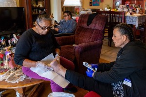 La abuela de Patricia Zamora la ayuda a limpiarse la herida. Zamora tuvo que dejar su puesto de supervisora. Fue desalojada y tuvo que mudarse con su hijo a la casa de sus padres, en Pomona, California. (Heidi de Marco/California Healthline)