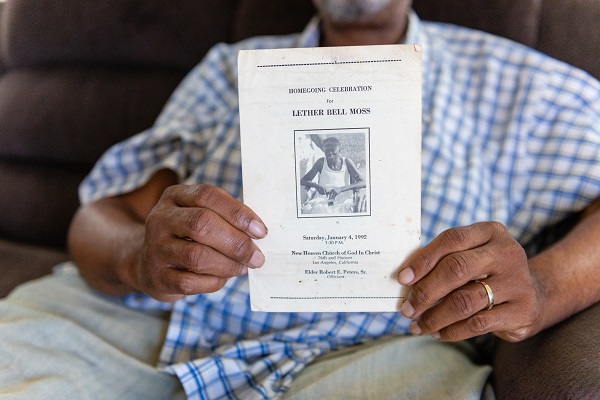 Jackson Moss holds the funeral program for his mother, who also had diabetes. (Heidi de Marco/Kaiser Health News)