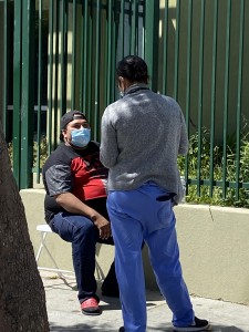 Hondureño sentado a la espera de su turno para la prueba de coronavirus platica con una enfermera.