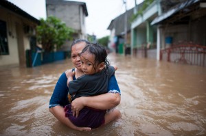 Una mujer carga a su hija tratando de ponerse a salvo durante las inundaciones en Yakarta, Indonesia. Foto: OMM/Kompas/Hendra A Setyawan / ONU.